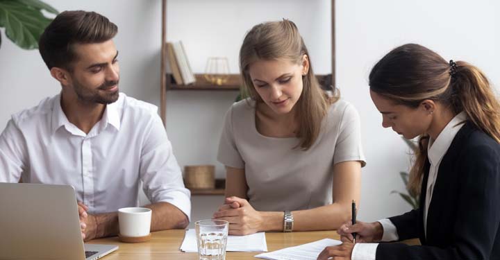 Tres empresarios sentados en una mesa viendo como uno escribe algo