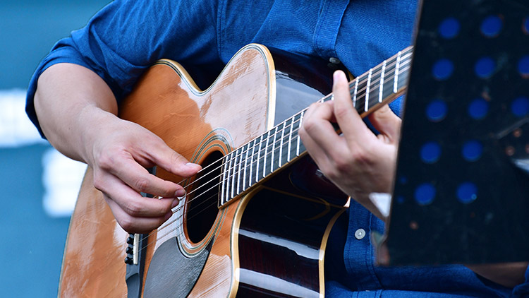 hombre con camisa azul tocando la guitarra en el estudio