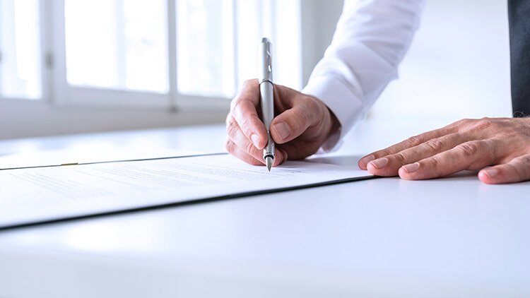 Hombre firma contrato con pluma