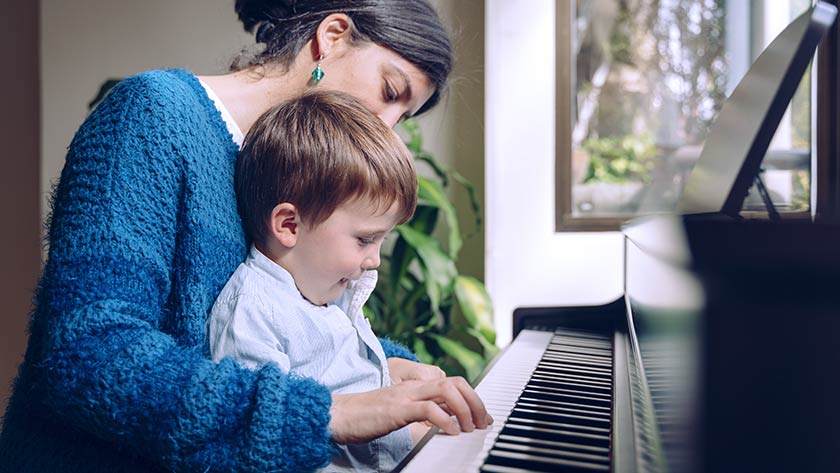 Madre sosteniendo a un niño en el regazo tocando el piano