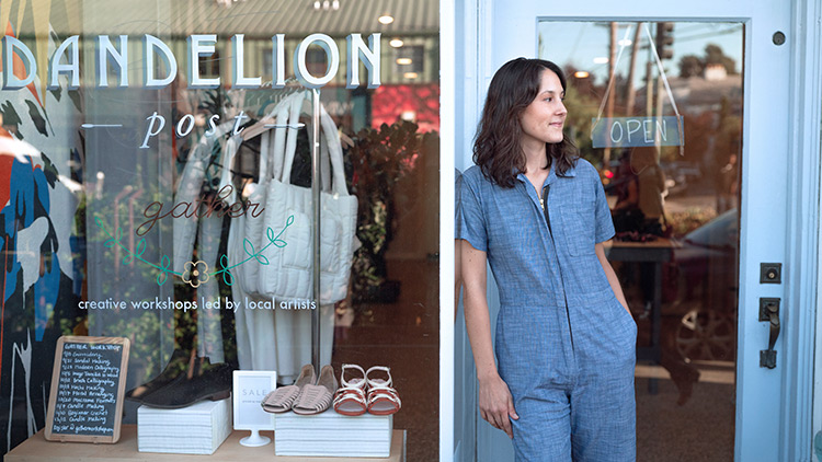 Dueño de una pequeña tienda de pie fuera del escaparate sonriendo