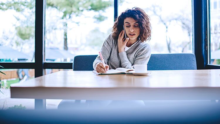 Mujer al teléfono tomando notas